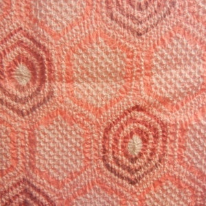 Puede incluir: Primer plano de una tela rosa y blanca con una superficie texturizada y un patrón repetitivo de círculos concéntricos.