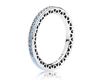 Könnte beinhalten: Ein silberner Ring mit einer Reihe kleiner hellblauer Steine am äußeren Rand. Die Seiten des Rings sind mit einem sich wiederholenden Muster aus schwarzen Herz-Ausschnitten verziert. Die Innenseite trägt die Gravur S925 ALE.