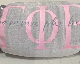 May include: A gray blanket with the Greek letters "ΓΦΒ" in pink, and the words "gamma phi beta" in gray script. The blanket is tied with gray ribbons with white polka dots.
