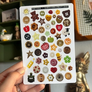 Pode incluir: Uma folha de botões decorativos em várias formas e cores, incluindo estrelas, corações e flores. Os botões são feitos de diferentes materiais e apresentam uma variedade de designs. O texto "BUTTONS - EARTHWORMCREATIONS" está impresso no topo.