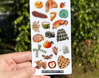 May include: A collection of fall-themed stickers featuring a variety of illustrations. The stickers include a waffle, a sleeping cat, a slice of pie, a fox, a sweater, a pumpkin, a deer, and more. The text "EARTHWORMCREATIONS" is printed on the bottom.