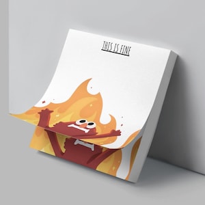 May include: A white notepad with the text "THIS IS FINE" printed in black. The notepad features a cartoon illustration of a red character in flames, with a distressed expression. The flames are yellow and orange.