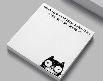 Puede incluir: Un bloc de notas blanco con el texto "EVERY SINGLE DAY THERE'S SOMETHING TO DO, AND I AM SICK OF IT." Una ilustración de gato negro está en la parte inferior. El bloc de notas está sobre una superficie gris.