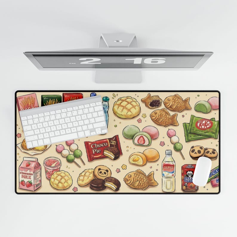 Puede incluir: Alfombrilla de escritorio beige con una variedad de aperitivos y dulces japoneses, incluyendo Kit Kat, Choco Pie y galletas con forma de panda. Un teclado y un rat&oacute;n blancos est&aacute;n sobre la alfombrilla, con un monitor de ordenador encima.