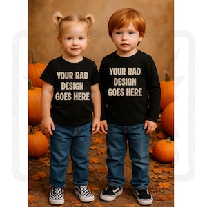 May include: Two children wearing black t-shirts and blue jeans stand in front of pumpkins and fall foliage. The shirts read "YOUR RAD DESIGN GOES HERE" in white text. One child wears a short-sleeved shirt, the other a long-sleeved shirt.