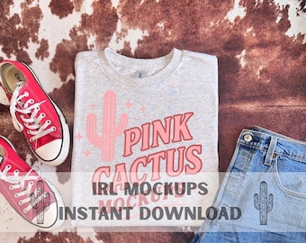 May include: A light grey t-shirt featuring a pink cactus design and the words "Pink Cactus". The image also shows red trainers, denim shorts with a cactus graphic, and the text "IRL MOCKUPS INSTANT DOWNLOAD".