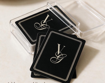 May include: A deck of black playing cards with a gold-colored monogram featuring the letters V and G in a script font, enclosed in a clear plastic case. The cards have a thin gold border and the text Add your wedding logo is visible below.