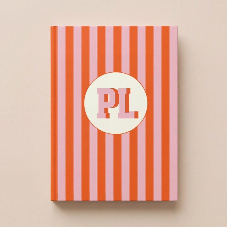Personalized striped hardcover notebook in orange and blush pink with custom monogram initials on a cream circle, luxury preppy journal gift for women, custom bridesmaid notebook, sorority style planner, aesthetic desk accessory, feminine stationery, personalized school notebook, chic office journal, monogram notebook for college student, stylish writing journal, custom name notebook gift, boutique stationery present, rich girl aesthetic desk decor, elegant striped diary, custom notebook
