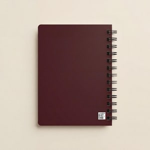 Blush pink spiral notebook featuring elegant white logo design displayed on a modern workspace desk with plant decor. Ideal for personalized business stationery, feminine branding, or executive office planners. Perfect for client gifts, event branding, and team journals. Aesthetic spiral notebook for creative professionals, business owners, and entrepreneurs who value modern, custom design office supplies.