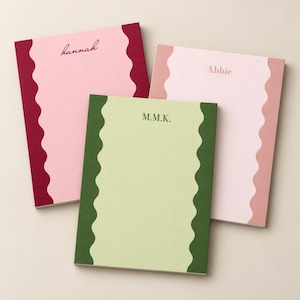 May include: Three rectangular paper notepads with wavy side borders. One notepad is light pink with dark red borders and the name hannah. Another is light green with dark green borders and M.M.K. The third is pale pink with dusty rose borders and Abbie.