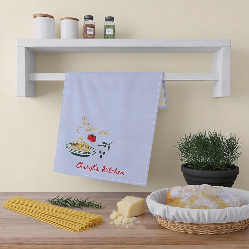 tea towel hanging elegantly beside marble cabinetry, decorative cooking accessory, tasteful residential textile, charming breakfast decor, polished entertaining accent, graceful farmhouse furnishing, refined household styling, cozy culinary atmosphere, fashionable apartment detail, beautiful woven material, elevated domestic presentation, curated kitchen aesthetic, sophisticated brunch companion, stylish pantry arrangement, delicate floral artwork, upscale homemaker favorite