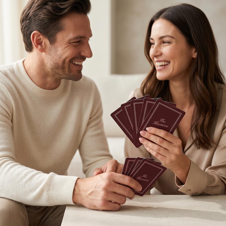 May include: A deck of playing cards with a navy blue card back featuring the text "The Millers" in a script font. The cards are arranged around the deck, with the Ace of Spades and a Joker card visible.