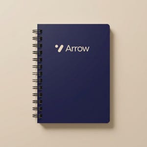 Clean white spiral notebook mockup featuring a centered blue geometric logo and “Custom Design Here” text. Ideal for businesses creating branded office supplies, promotional event notebooks, and personalized company planners. Perfect for entrepreneurs, startups, and corporate teams seeking cohesive branding materials. Sleek, modern spiral notebook for professional use, journaling, and team appreciation gifts.