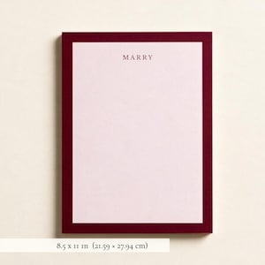 May include: A rectangular sheet of stationery featuring a pale pink center bordered by a thick, dark burgundy frame. The word MARRY is printed in dark burgundy capital letters at the top center. The paper measures 8.5 by 11 inches.