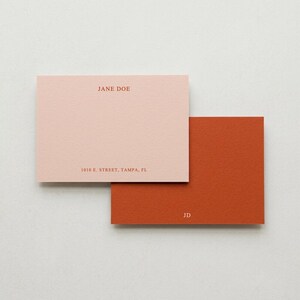 May include: Two square notecards, one blush pink and one burnt orange, with a textured finish. The pink card has the name "JANE DOE" and address printed in a matching color. The orange card has the initials "JD".