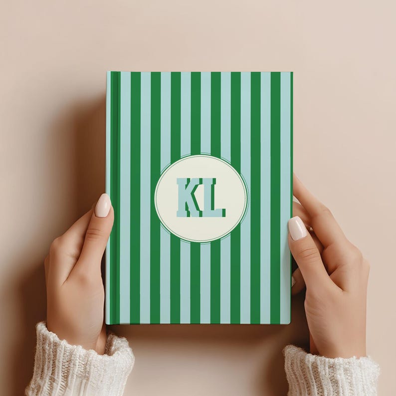 Green and light blue striped personalized notebook held in hands, featuring custom initials on the cover. Monogrammed hardcover journal with lined perforated pages for writing, journaling, or planning. Elegant aesthetic notebook for office, school, or personal use. Custom name notebook ideal for professionals, students, or gift-giving. Stylish green stripe stationery perfect for daily notes, business meetings, or thoughtful personalized gifts.