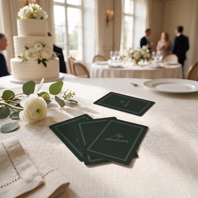 May include: A stack of rectangular dark forest green cards with rounded corners. Each card features a thin, double-lined white border and the text "The Blackburns" printed in a white, elegant, cursive script font centered on the front surface.