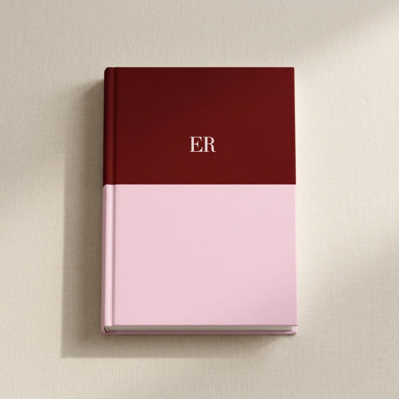 May include: A hardcover book featuring a two-tone color scheme with a deep burgundy upper section and a soft light pink lower section. The letters ER are printed in a clean, white serif font centered on the burgundy portion of the front cover.