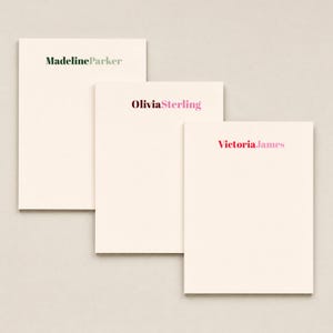 May include: Three rectangular cream-colored stationery cards arranged in a staggered stack. Each card features a printed name in a serif font: MadelineParker in dark green, OliviaSterling in dark pink and magenta, and VictoriaJames in red and pink.