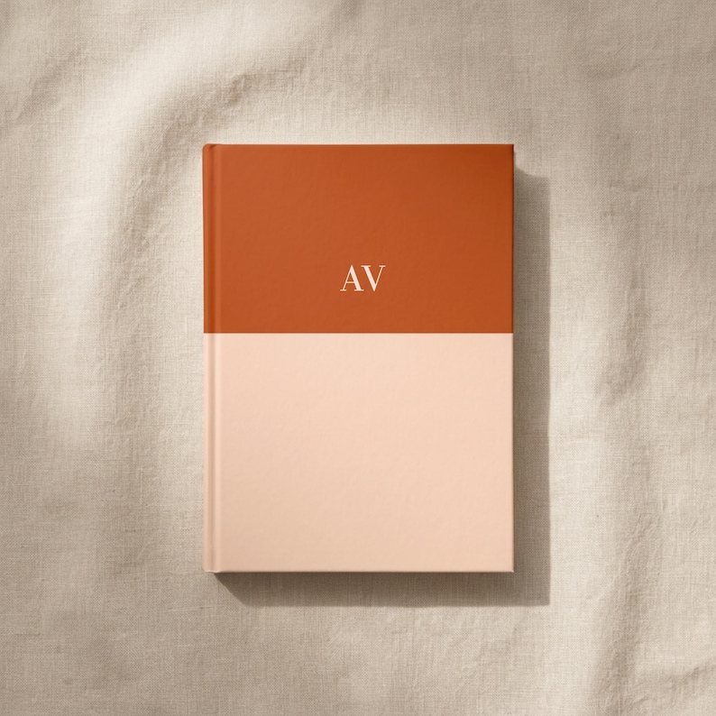 Flat lay of a personalized burnt orange and blush color block hardcover notebook with gold monogram initials on a soft neutral linen background, luxury stationery gift, custom journal, elegant desk accessory, premium writing notebook, modern monogram planner, personalized note taking journal, aesthetic office notebook, gift for professionals, bridesmaid gift idea, office organization stationery, high end paper goods, daily planner, and journaling notebook for work and school.