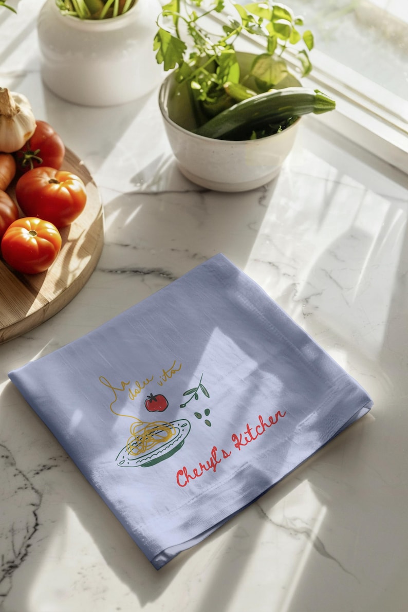 Botanical kitchen towel draped across elegant oven bar, watercolor blossom artwork, spring cottage furnishing, culinary enthusiast accessory, upscale entertaining detail, airy breakfast nook styling, pastel floral textile, charming domestic accent, handcrafted aesthetic, feminine cooking decor, tasteful laundry cloth, curated apartment furnishing, rustic chic presentation, sophisticated dining atmosphere, everyday household staple, luxury homemaker essential, refined baking setup
