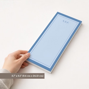 Puede incluir: Un bloc de notas azul claro con un borde azul oscuro y las iniciales "A.S.F." en la esquina superior derecha. El bloc de notas mide 9,4 cm x 24,13 cm.