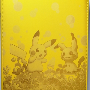 Puede incluir: Una carpeta de color amarillo brillante con un gráfico impreso de Pikachu y Mimikyu de pie en un campo de plantas y bayas estilizadas. El fondo incluye un patrón sutil de círculos de color amarillo claro y la cubierta tiene un acabado texturizado.