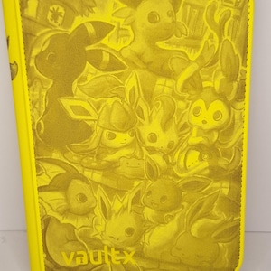 May include: A yellow card binder featuring a repeating pattern of cartoon characters. The binder has a zipper closure and the word "vaultx" is printed in the lower left corner. The overall design is a monochromatic yellow.