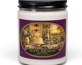 May include: A white candle in a clear glass jar with a black lid. The label features a purple border and an oval illustration of a birthday cake on a table with the text HAPPY BIRTHDAY, Make a Wish... HERITAGE HOUND MARKET.