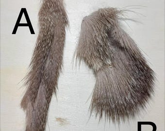 May include: Two pieces of fur, labeled A and B, against a light wood background. Fur A is a long, slender piece, while Fur B is a shorter, more irregular shape. Both pieces have a mix of brown and gray tones, with visible texture.