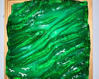 May include: A vibrant, abstract artwork featuring a textured, glossy green surface within a wooden frame. The piece has a layered appearance with flowing lines and a few white bird silhouettes, evoking a sense of nature and landscape.