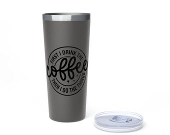 May include: A gray stainless steel tumbler with a silver rim and a clear lid. The tumbler has the text "FIRST I DRINK THE coffee THEN I DO THE THINGS" in a black circular design. The tumbler is designed to keep beverages hot or cold.