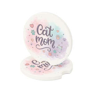 May include: Two white car coasters with a watercolor design. The top coaster has the words "Cat Mom" in cursive, surrounded by hearts, paw prints, and a cat illustration. The bottom coaster has the word "me".