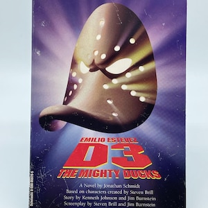May include: A paperback book titled D3 The Mighty Ducks by Jonathan Schmidt, featuring a brown duck-shaped goalie mask on a purple background. The cover includes the text Emilio Estevez, the title, and the Scholastic logo at the bottom left corner.