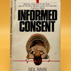 May include: A paperback book titled "Informed Consent" by Neil Ravin. The cover features a person inside a medical device and the title in large, bold letters. The book is a medical thriller.