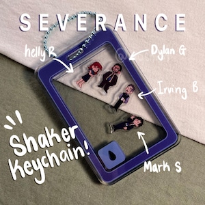May include: A purple shaker keychain with the word "SEVERANCE" at the top. The keychain features cartoon figures of characters and the text "Shaker Keychain!"