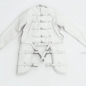 Könnte beinhalten: Weiße Lederjacke mit mehreren Riemen und Schnallen. Die Jacke hat lange Ärmel und ein gestepptes Schulterdesign. Die Riemen sind mit Metallschnallen befestigt. Die Jacke liegt auf einer weißen Oberfläche.