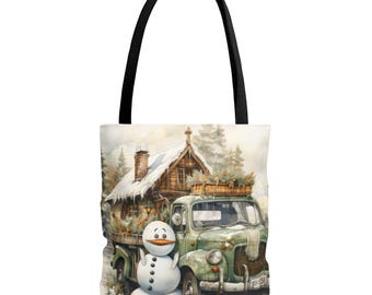 May include: Tote bag featuring a watercolor illustration of a vintage green truck carrying a load of greenery, a snowman, and a snow-covered cabin. The bag has a black handle and is perfect for carrying groceries or books.