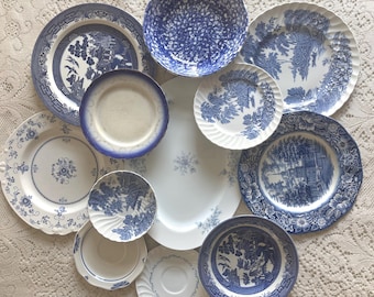 May include: A collection of assorted ceramic dinnerware including several plates, bowls, and a large oval platter. The pieces feature various blue and white patterns, including willow motifs, floral designs, and landscape scenes on white backgrounds.