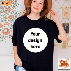 May include: Black t-shirt with a white circle in the center, featuring the text "Your design here." The shirt is a solid black color. The image also includes a logo that says "PRETTIFY PRINTS DTF SUPPLY."