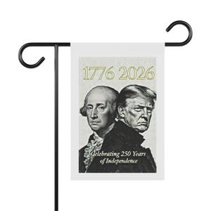 以下が含まれることがあります： ジョージ・ワシントンとドナルド・トランプの肖像画が描かれた白いガーデンフラッグ。金色の文字で「1776 2026」と「Celebrating 250 Years of Independence」と書かれています。旗は黒い金属製のスタンドに取り付けられています。