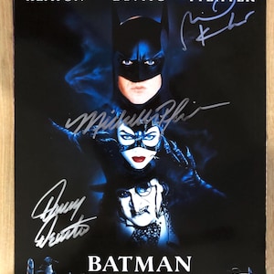 Może przedstawiać: Plakat filmowy do filmu "Powrót Batmana" z Michaelem Keatonem, Dannym DeVito i Michelle Pfeiffer. Plakat zawiera podpisy i tytuł "Batman Returns" na dole. Tło jest ciemnoniebieskie z wizerunkami postaci.