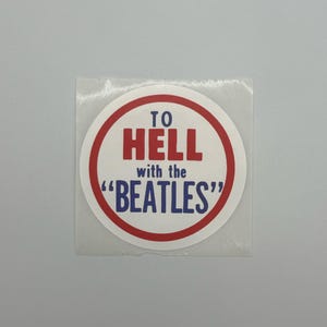 May include: A circular sticker with a red and white border. The text "TO HELL with the 'BEATLES'" is printed in red and blue. The sticker is on a clear backing.