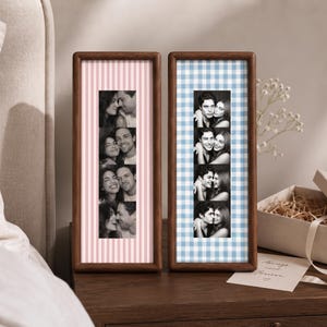 Könnte beinhalten: Zwei rechteckige Holzrahmen mit vertikalen Fotostreifen. Der linke Rahmen hat einen rosa-weiß gestreiften Hintergrund, der rechte Rahmen einen blau-weiß karierten Hintergrund. Jeder Streifen zeigt vier Schwarz-Weiß-Fotos.