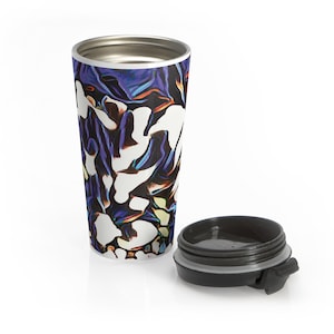 May include: A stainless steel travel mug with a black lid. The mug features a vibrant abstract design in shades of blue, purple, white, and yellow. The lid is detached and placed next to the mug.
