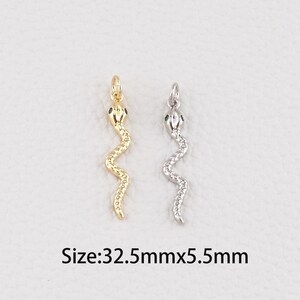 Peut inclure: Deux pendentifs en forme de serpent, un doré et un argenté, avec des accents verts sur la tête. Le pendentif doré est à gauche, et l'argenté à droite. Dimensions : 3,25 cm x 0,55 cm.