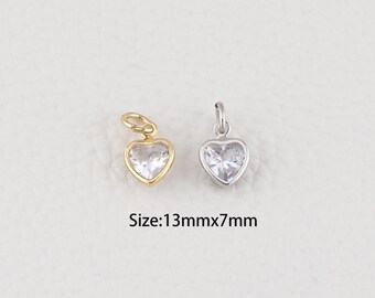Puede incluir: Dos colgantes en forma de corazón, uno dorado y otro plateado, cada uno con una piedra transparente facetada. El colgante dorado tiene una anilla dorada, y el colgante plateado tiene una anilla plateada. Tamaño: 13mm x 7mm.