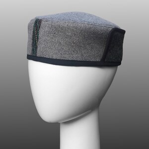 May include: A gray felt hat with a black trim and a colorful stripe down the side. The hat is on a white mannequin head.