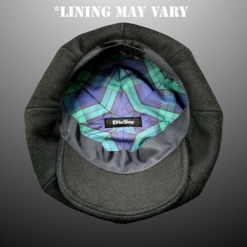 May include: The inside of a black wool newsboy cap with a plaid lining. The lining is green, blue, and black. A label with the text "IDHatShop" is sewn into the lining.