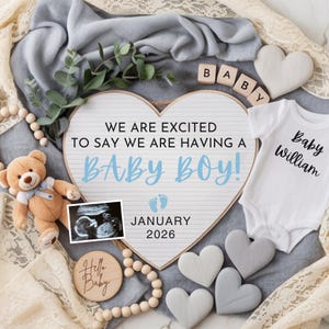 May include: An announcement with a heart-shaped sign that reads "WE ARE EXCITED TO SAY WE ARE HAVING A BABY BOY!" with the expected due date of January 2026. Includes a teddy bear, baby onesie, ultrasound image, and wooden hearts.